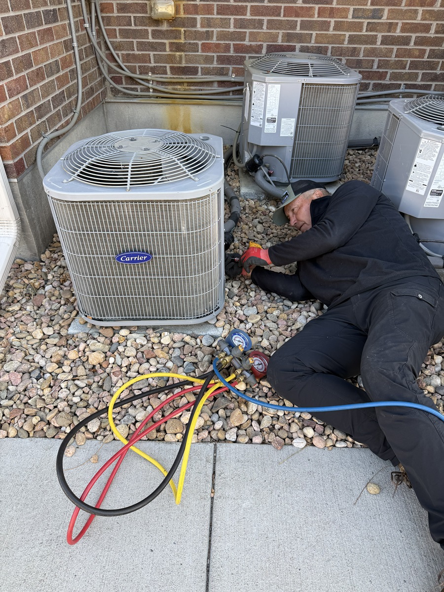 HVAC Technician laying on his back working on an air conditioner