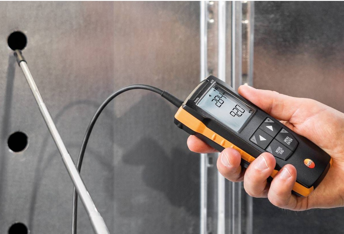 ac technician checking air flow with a tool