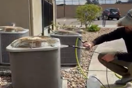 person cleaning and air conditioiner coil with a sprayer