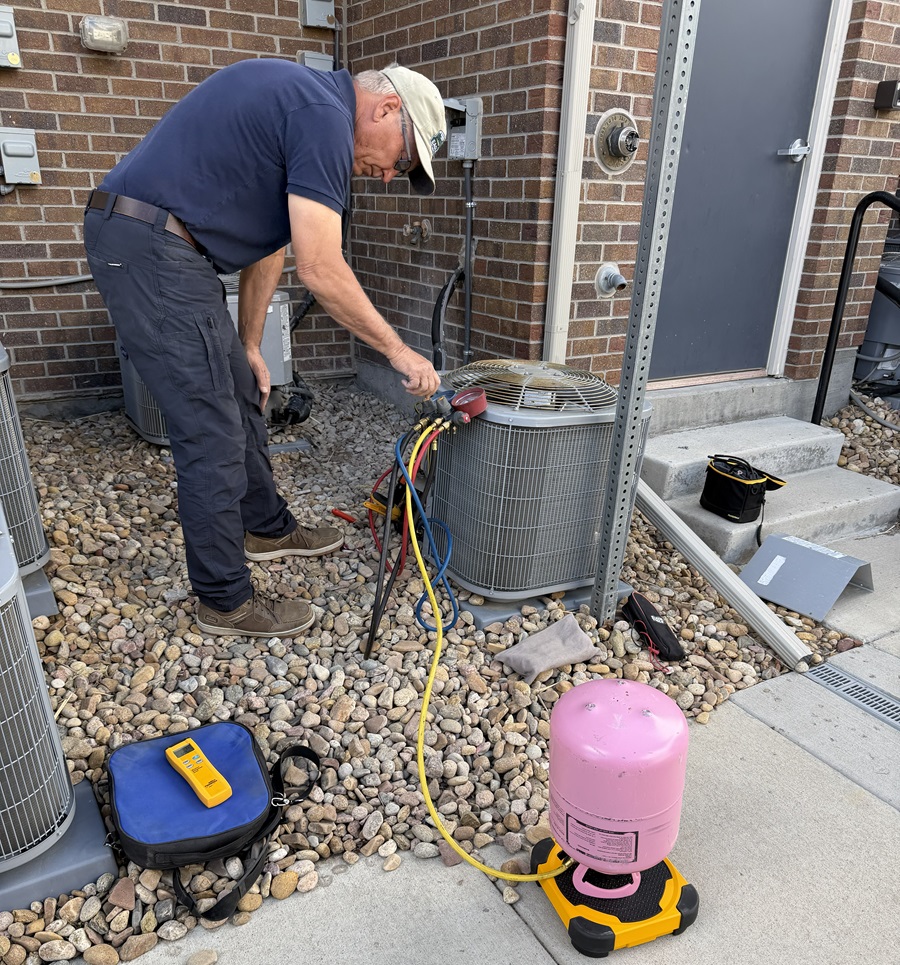 air conditioning repair technician charging a a/c unit