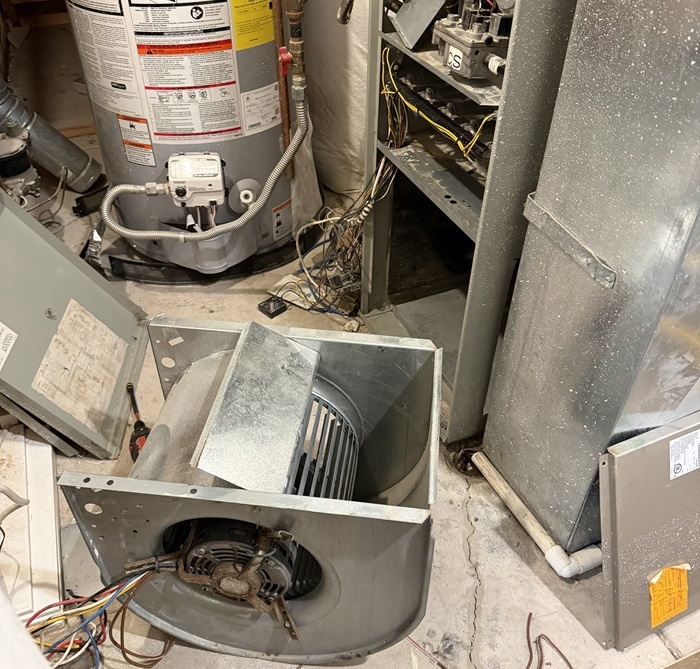 Furnace cabinate being repaired with a blower on the floor