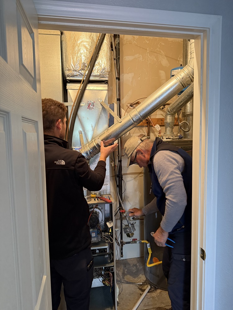 Two technicians tuning up a furnace