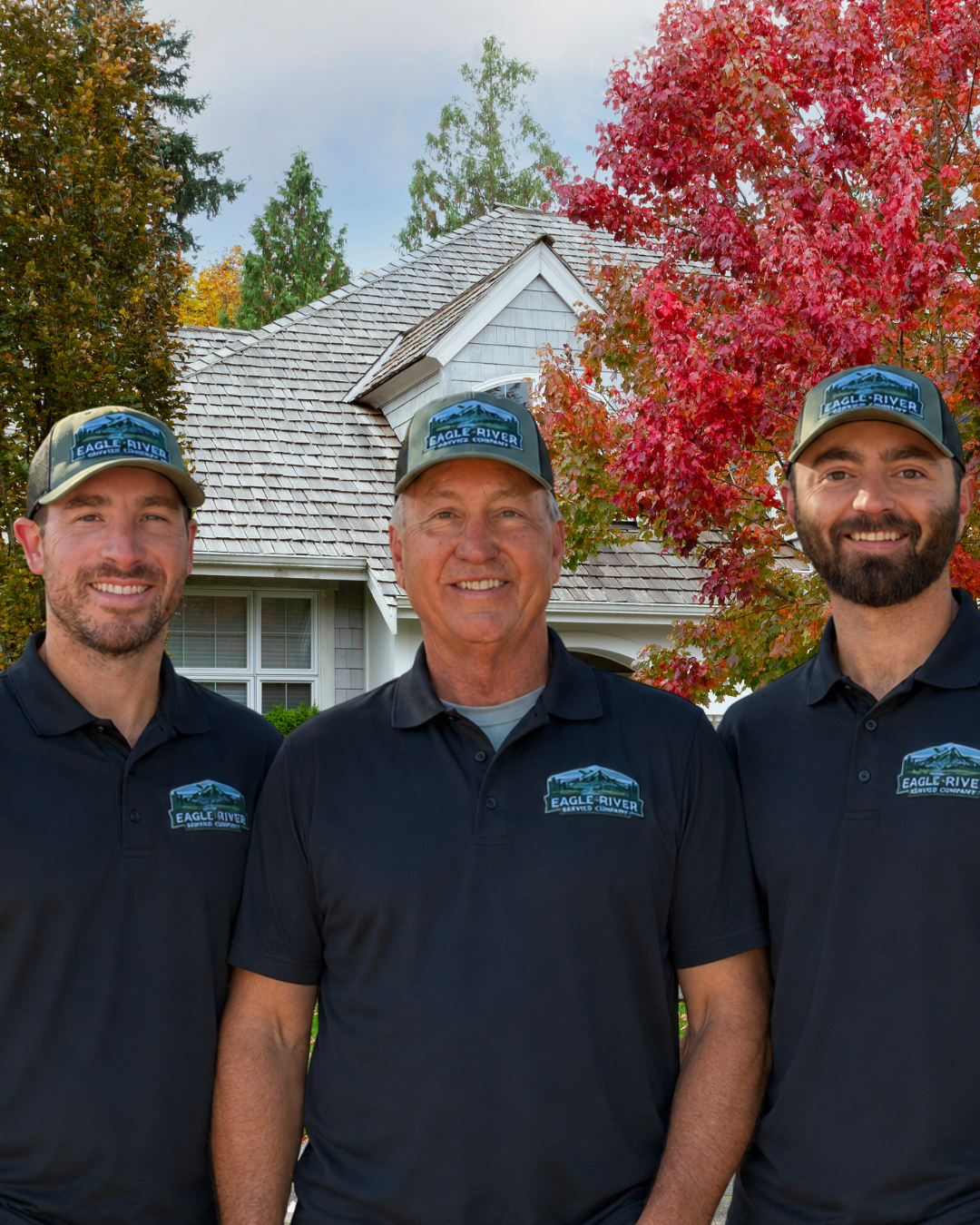HVAC Technicians standing infront of a house with a tree with red leaves